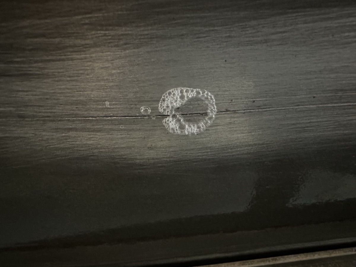 Small aluminum spot weld repair on a dark metal surface