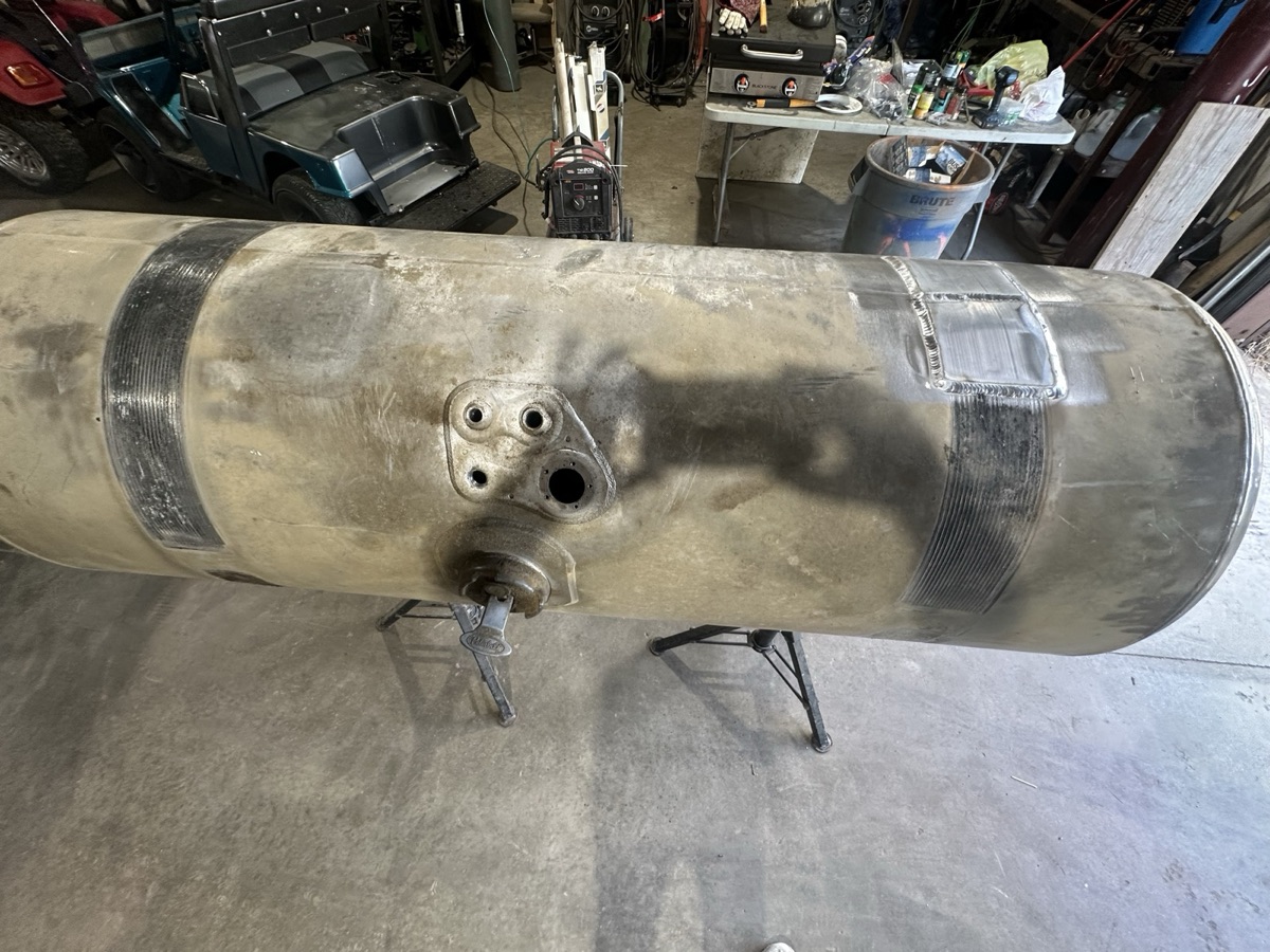 Large aluminum tank on jack stands with weld bands in the shop