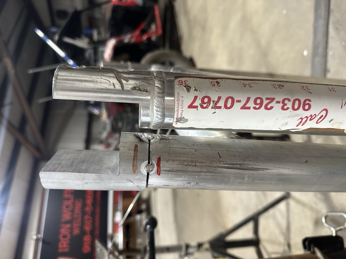 Aluminum tube sections with weld repair set up alongside the Iron Wolfe banner