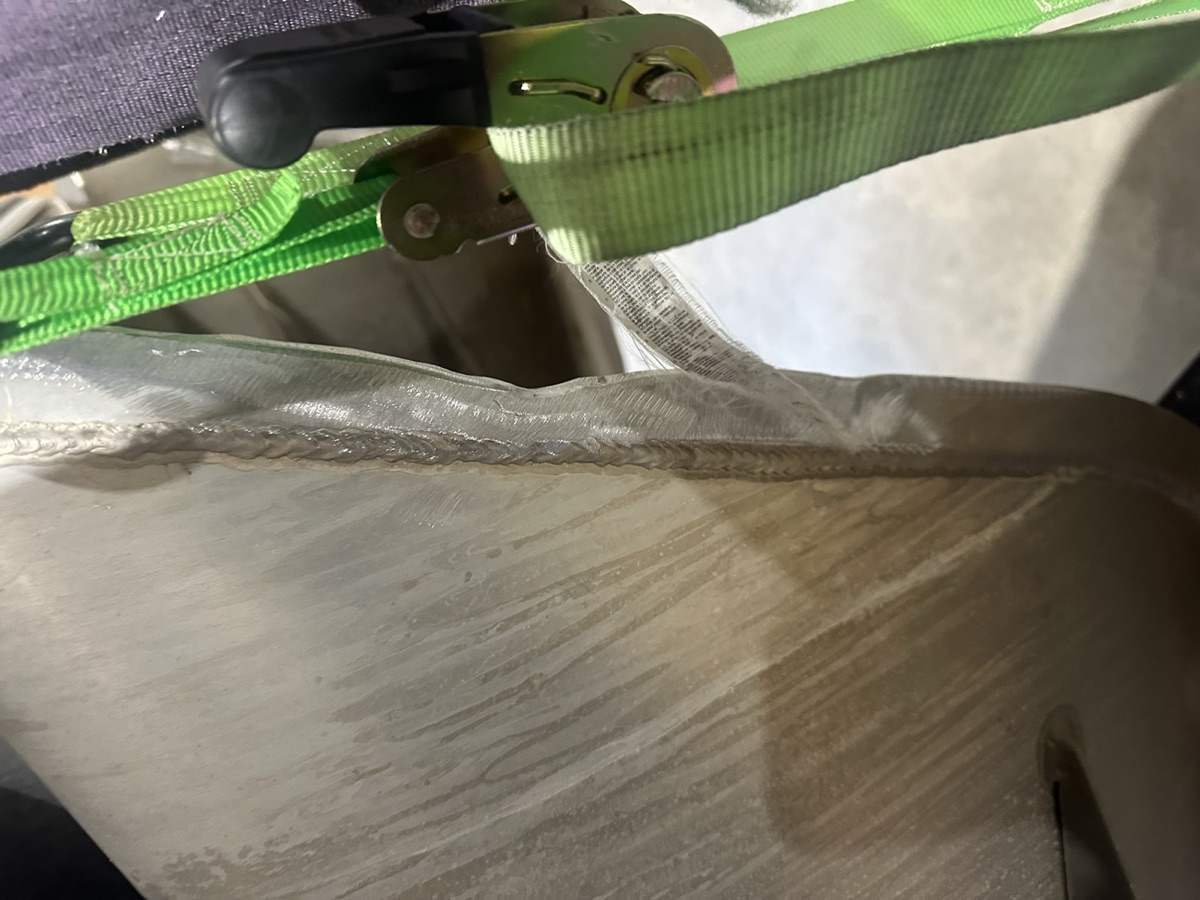 Close-up of an aluminum weld seam with ratchet strap