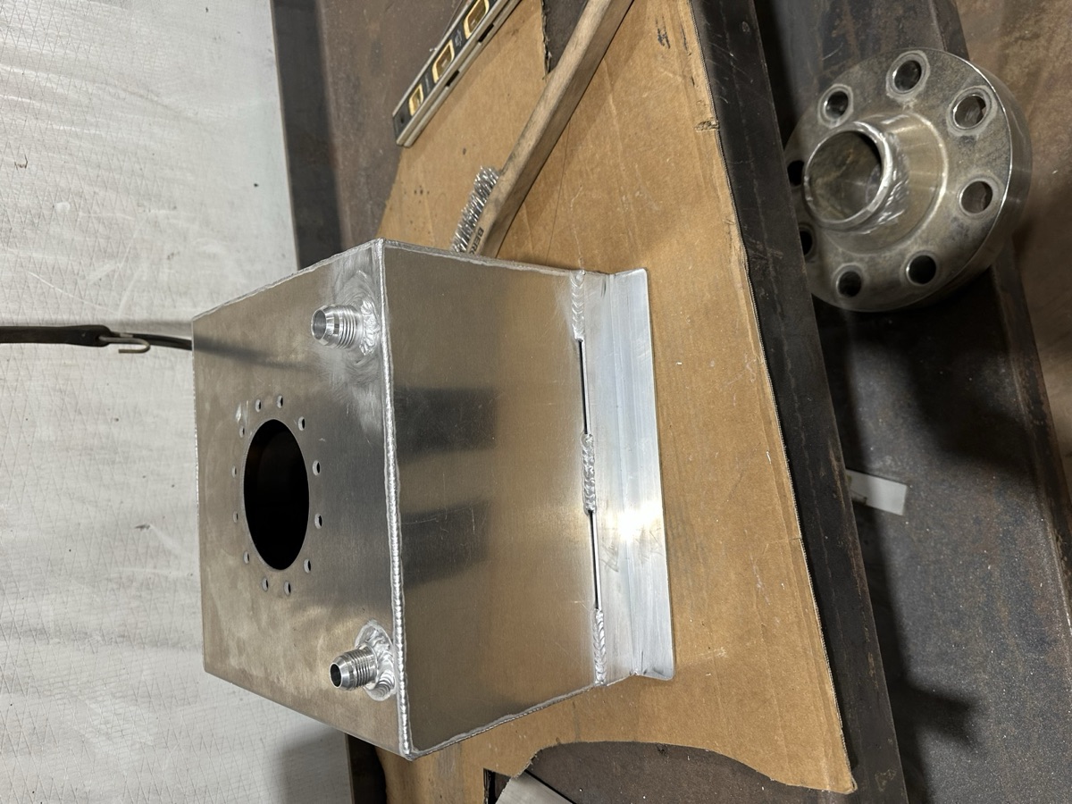 Custom-fabricated aluminum tank with welded fittings on a workbench