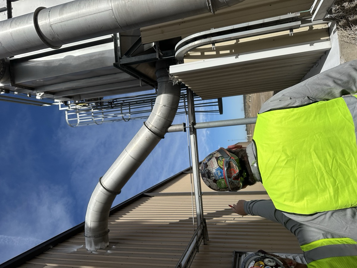 Workers in safety vests inspecting industrial piping at an outdoor job site