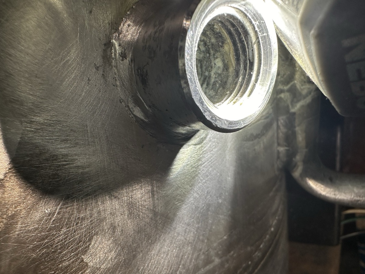 Interior view of a tank bung fitting welded into a metal vessel