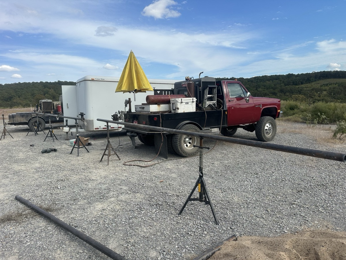 Mobile welding rig truck set up at an outdoor job site with pipe on stands