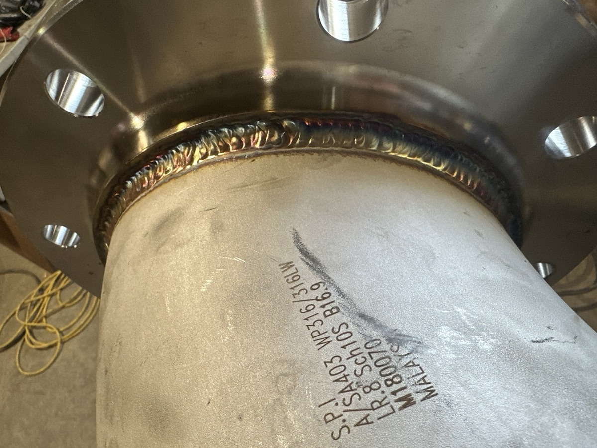Stainless steel pipe elbow welded to a flange with SA403 marking visible