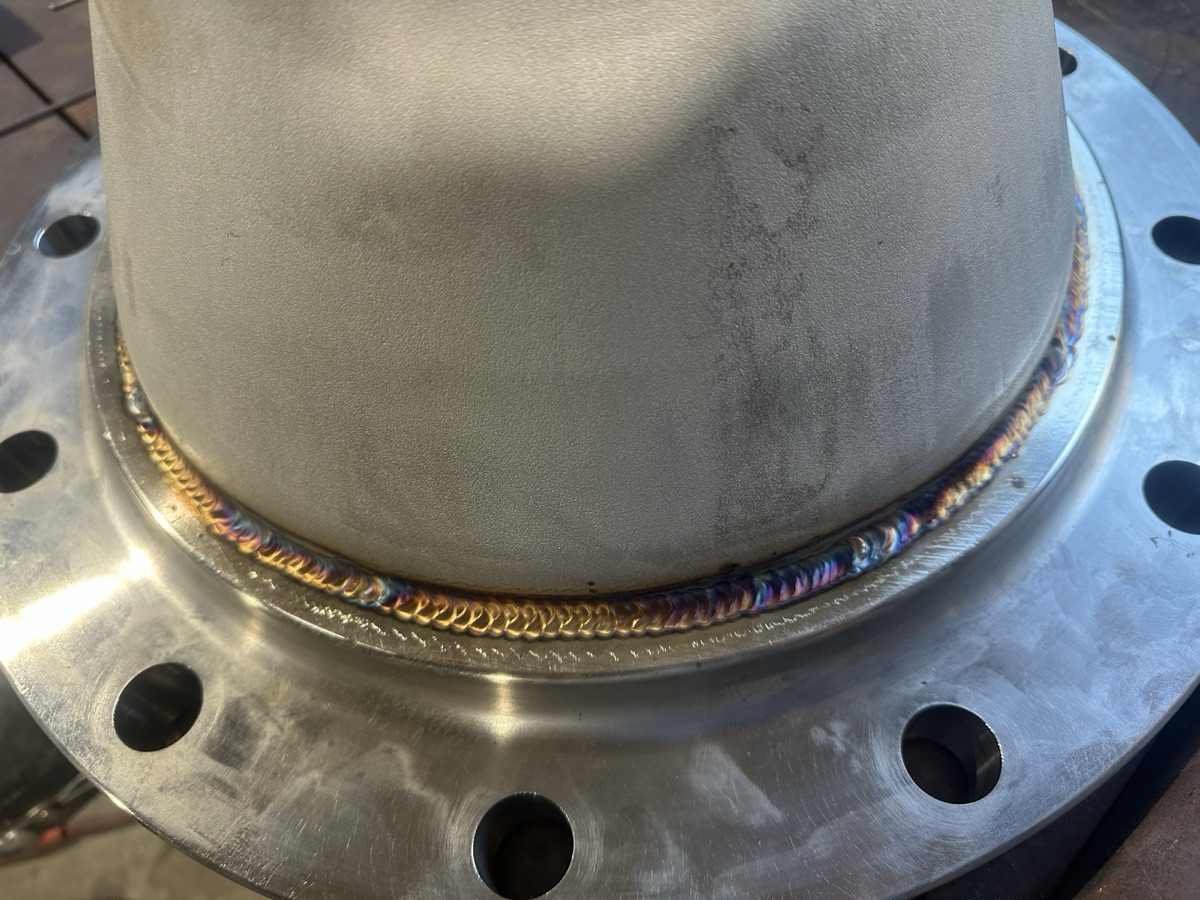 Close-up of a precision weld bead on a stainless steel pipe-to-flange joint