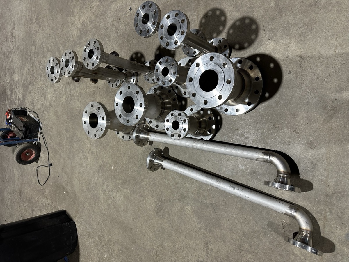 Batch of stainless steel pipe spools and flanges laid out on the shop floor