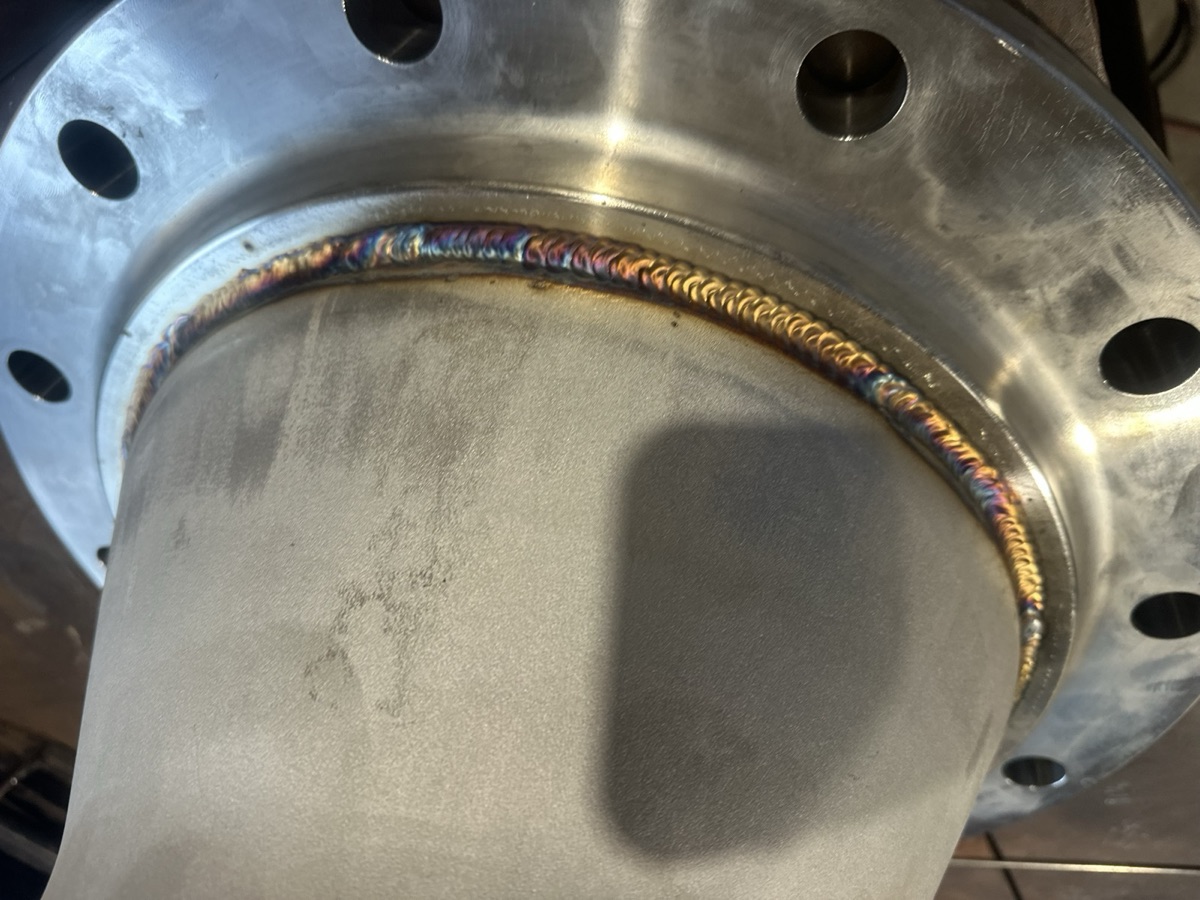 Stainless steel pipe welded to a flange showing heat-tinted precision weld bead
