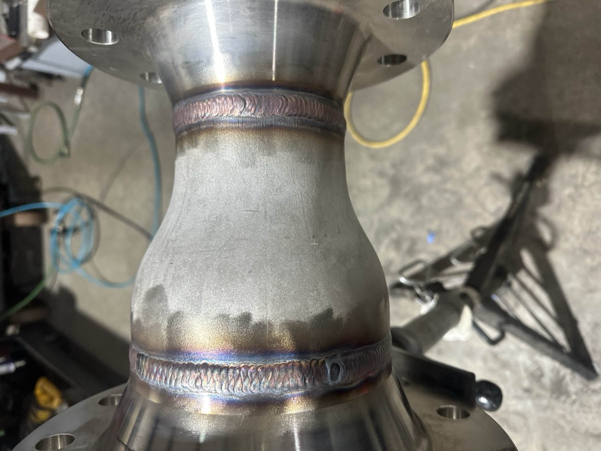Stainless steel reducer with flanges and TIG weld beads on a jack stand
